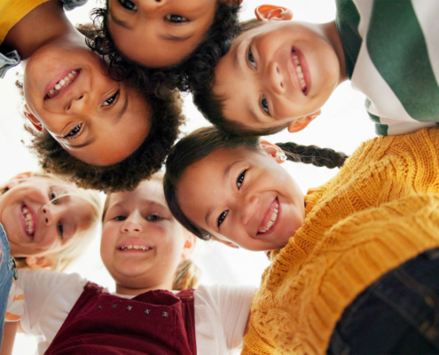 Worm's Eye View Of A Huddle Of Children Looking At The Camera